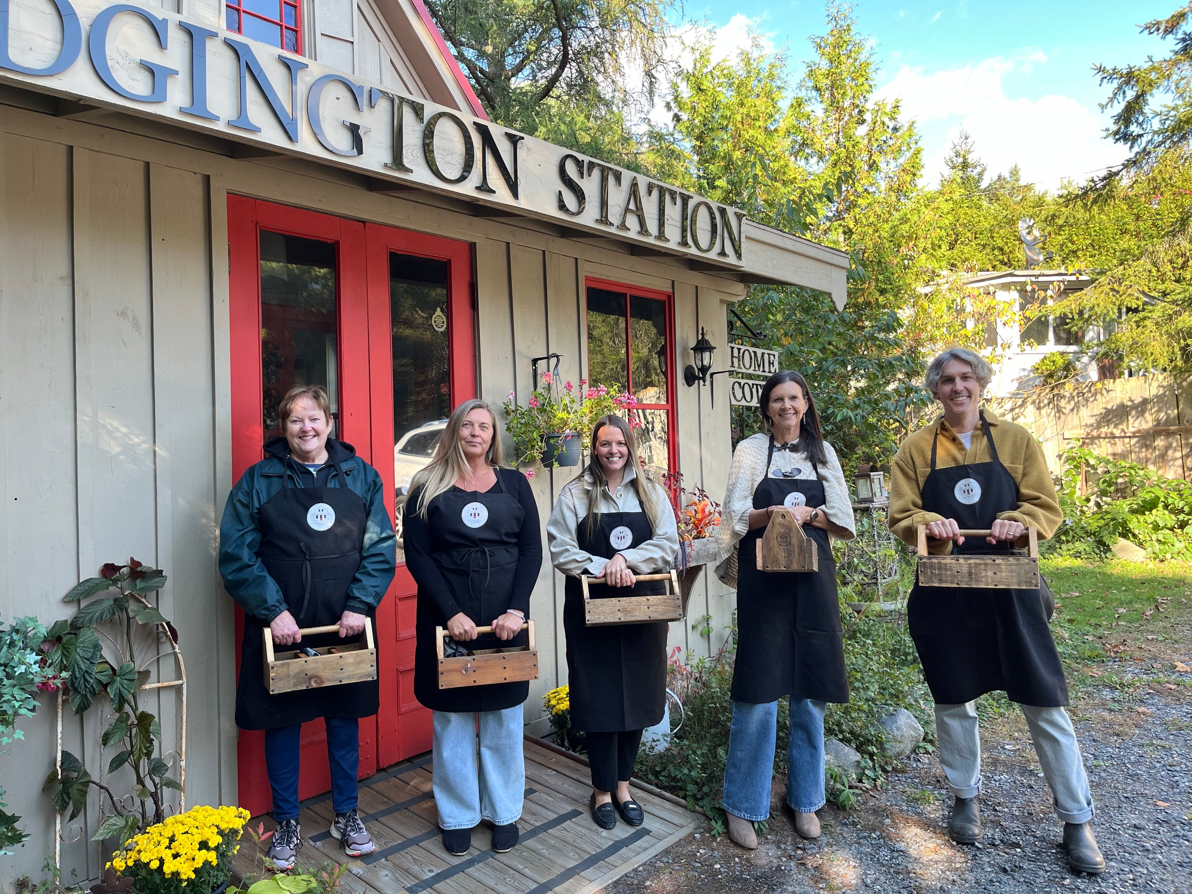 A group of workshop participants in aprons proudly display their salvaged wood tote boxes