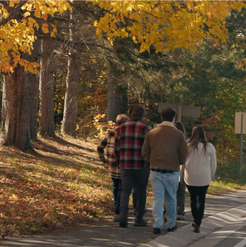 A small group walking on a country road in the village of Orrville in fall