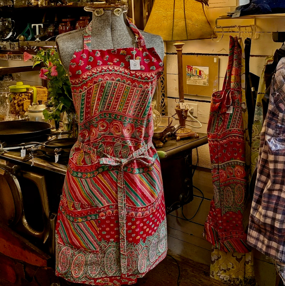A colourful paisley and geometric patterned apron on a mannequin in an old kitchen setting