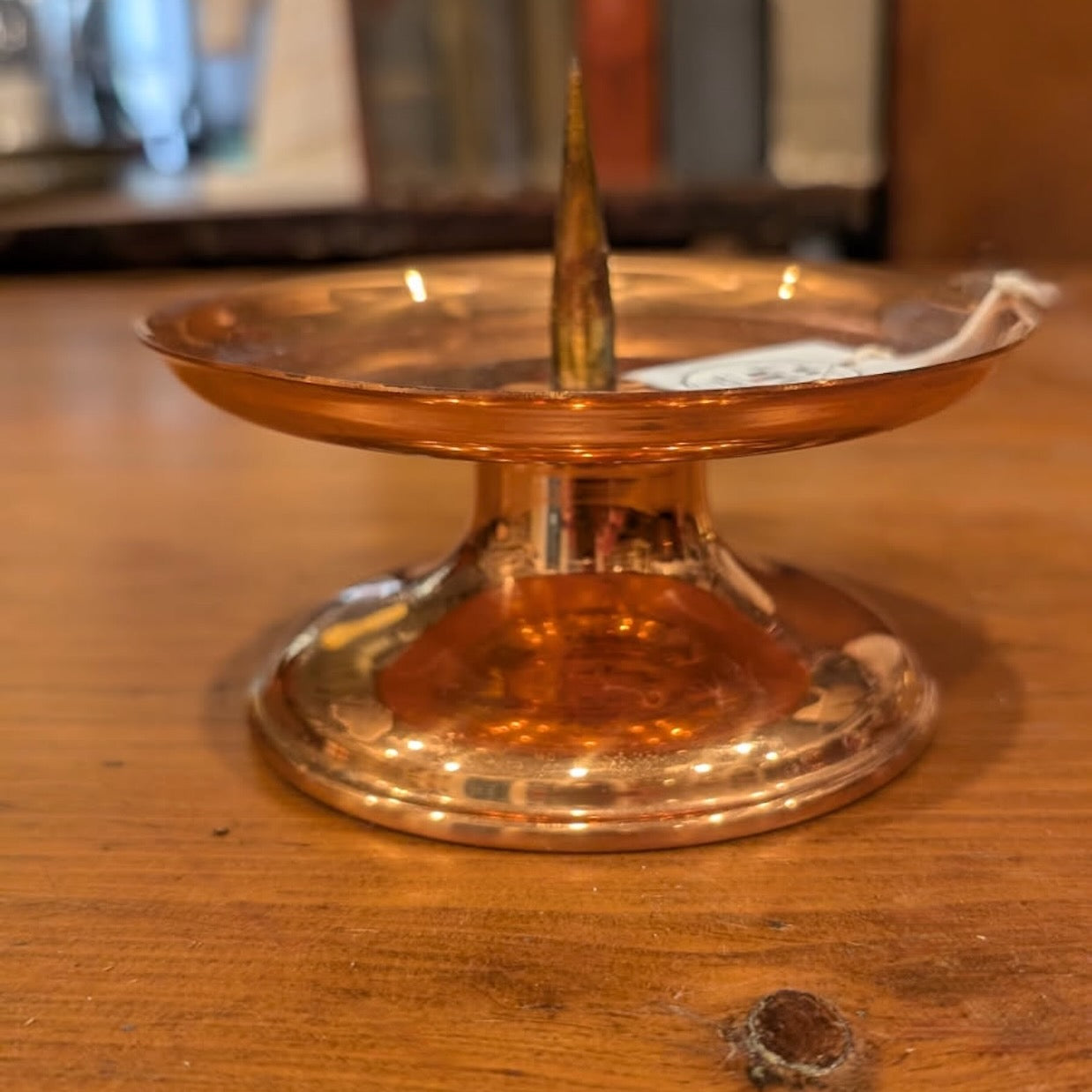Copper candleholder with a slightly worn finish on a wooden surface