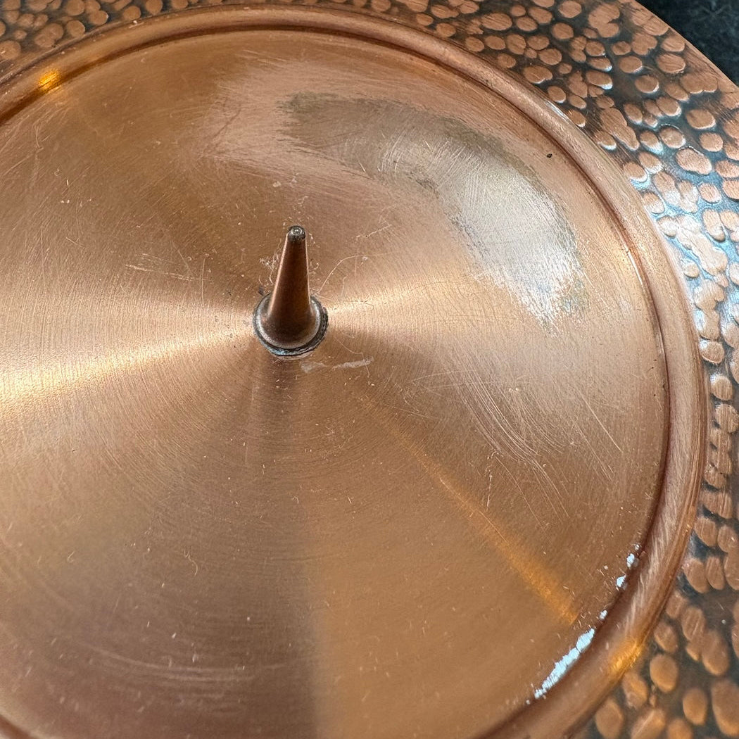 Close-up of a copper candleholder showing damage to the copper finish  