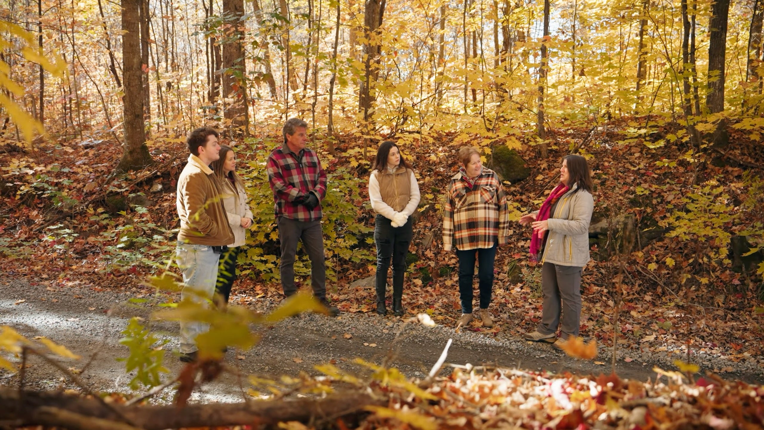A small tour group stands in the woods on a beautiful autumn day