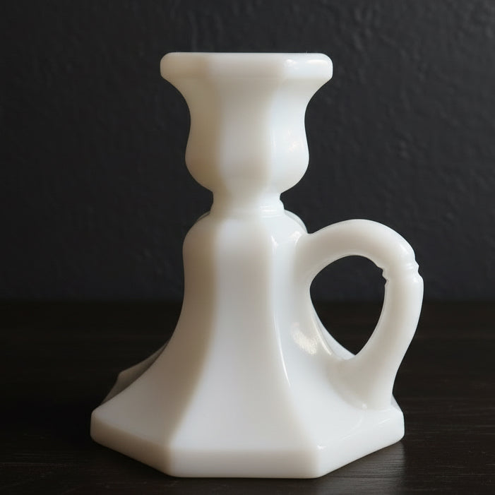 Side view of a white milk glass candle holder with handle on a dark background