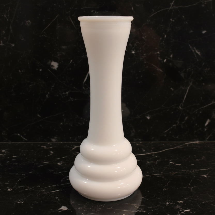 White glass vase on a dark marble surface with a black background