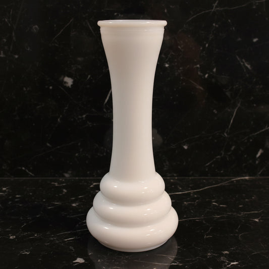 White glass vase on a dark marble surface with a black background