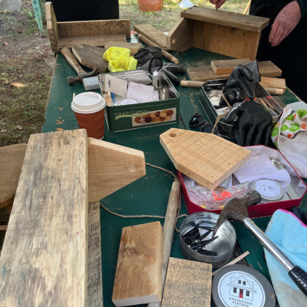 Workbench with wooden boards, tools,  nails, and a coffee cup outdoors