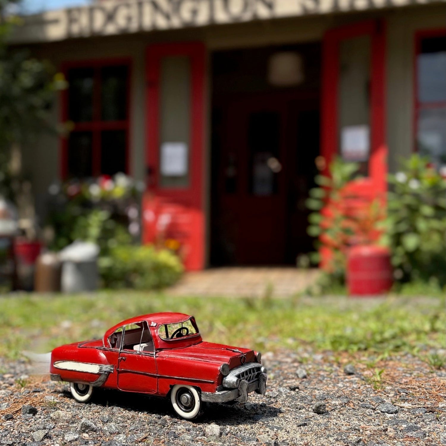 A red vintage model classic car in front of a building with a red door.