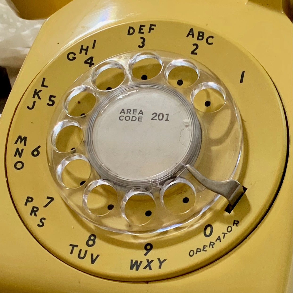 The numbers on the dial of an old yellow rotary phone