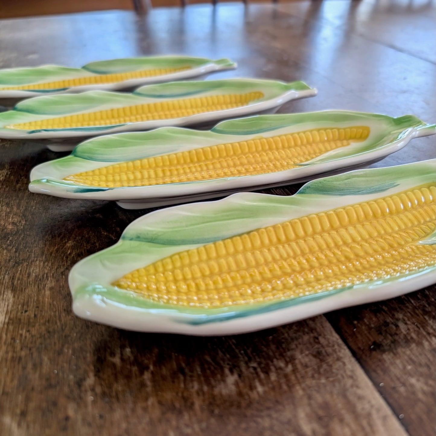 Closeup showing sculptural detail of a set of ceramic corn on the cob plates on a wooden surface