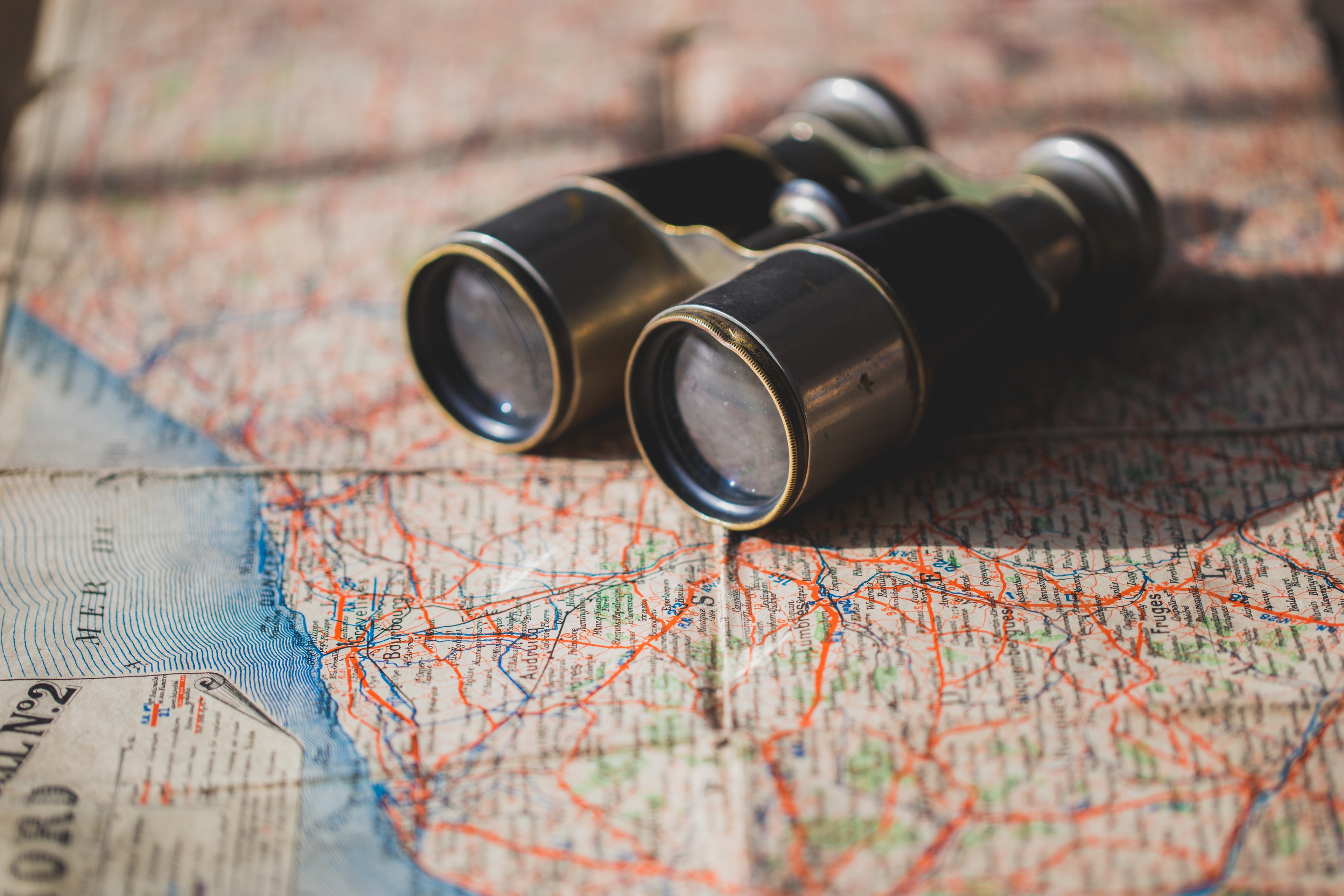 Vintage binoculars sit on an old map